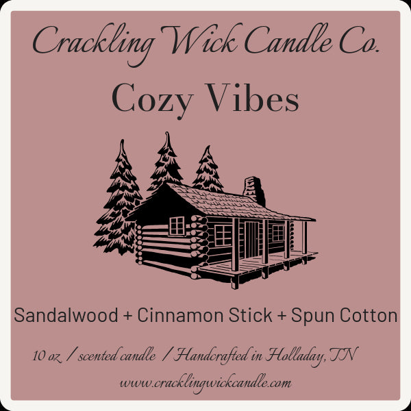 Cozy Vibes scented candle with cabin-and-trees label; Sandalwood + Cinnamon Stick + Spun Cotton