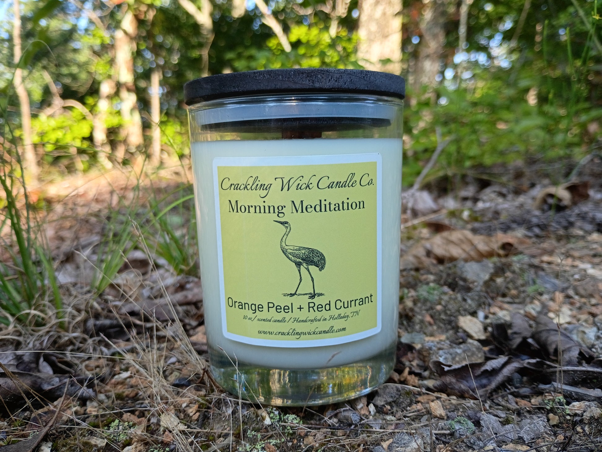 Candle jar with black lid, green label, and pale blue wax
