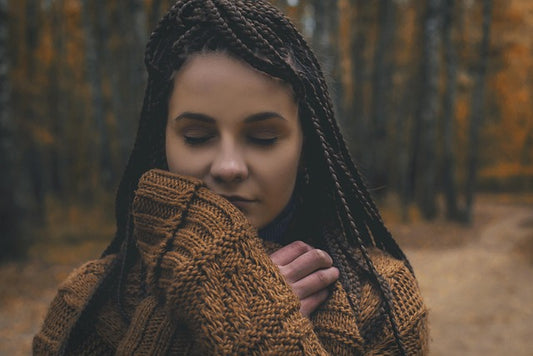 Woman holding a brown knit scarf near her face
