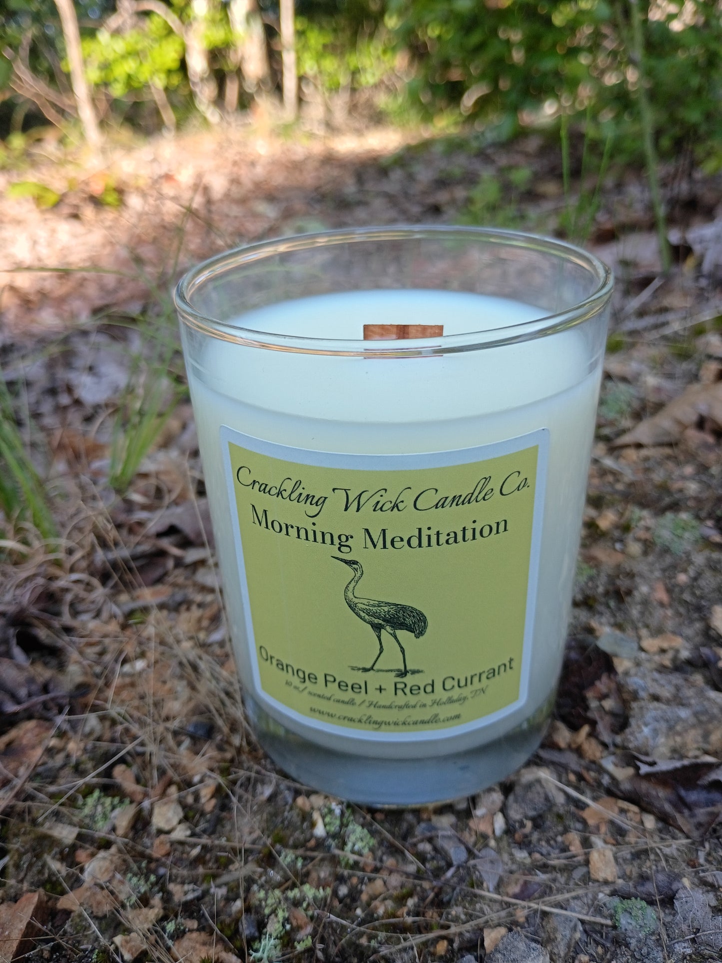 Light blue glass jar candle with green label and exposed copper wick tab
