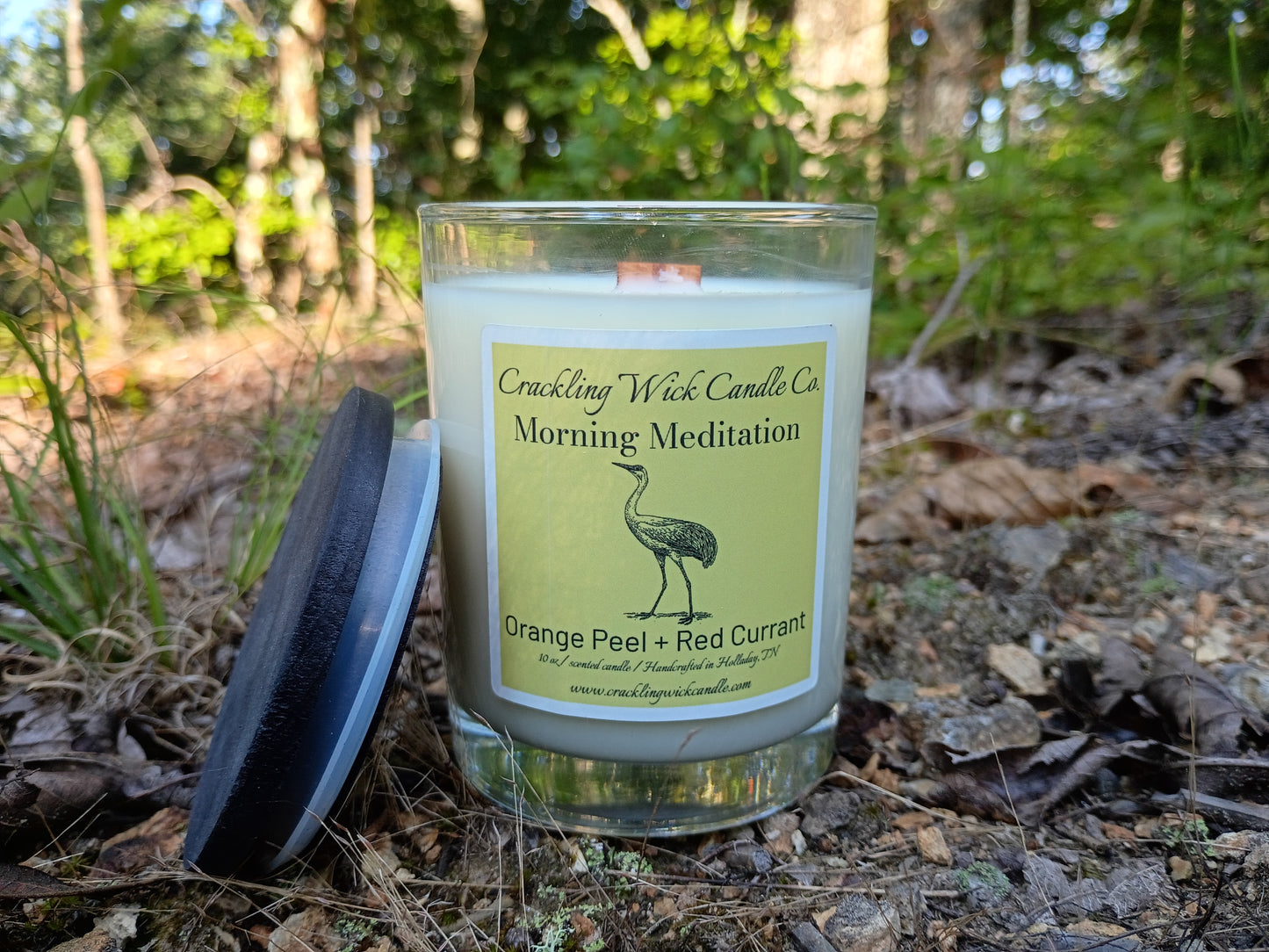 Candle jar with green label, pale blue wax, and glass lid outdoors