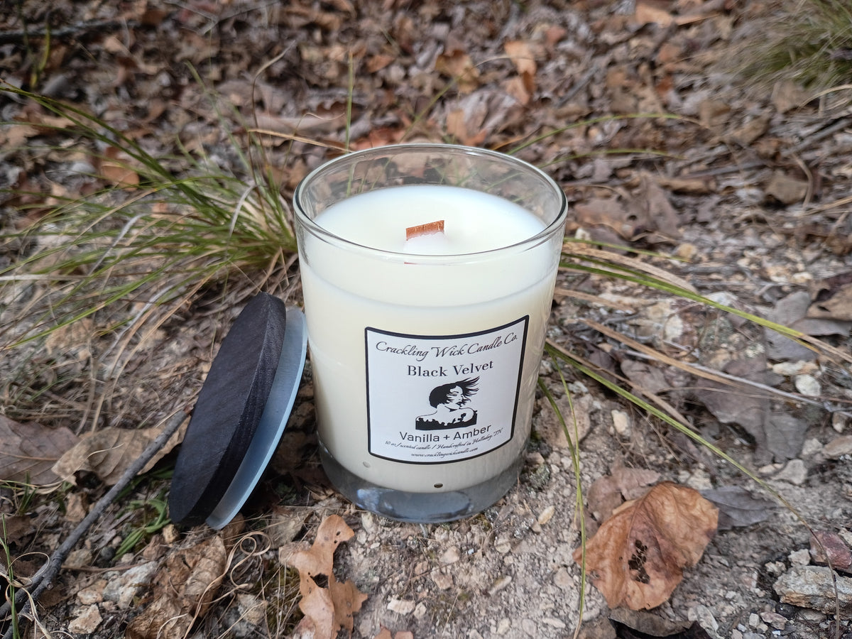 Black velvet candle in clear glass jar, white wax and printed label, visible wick