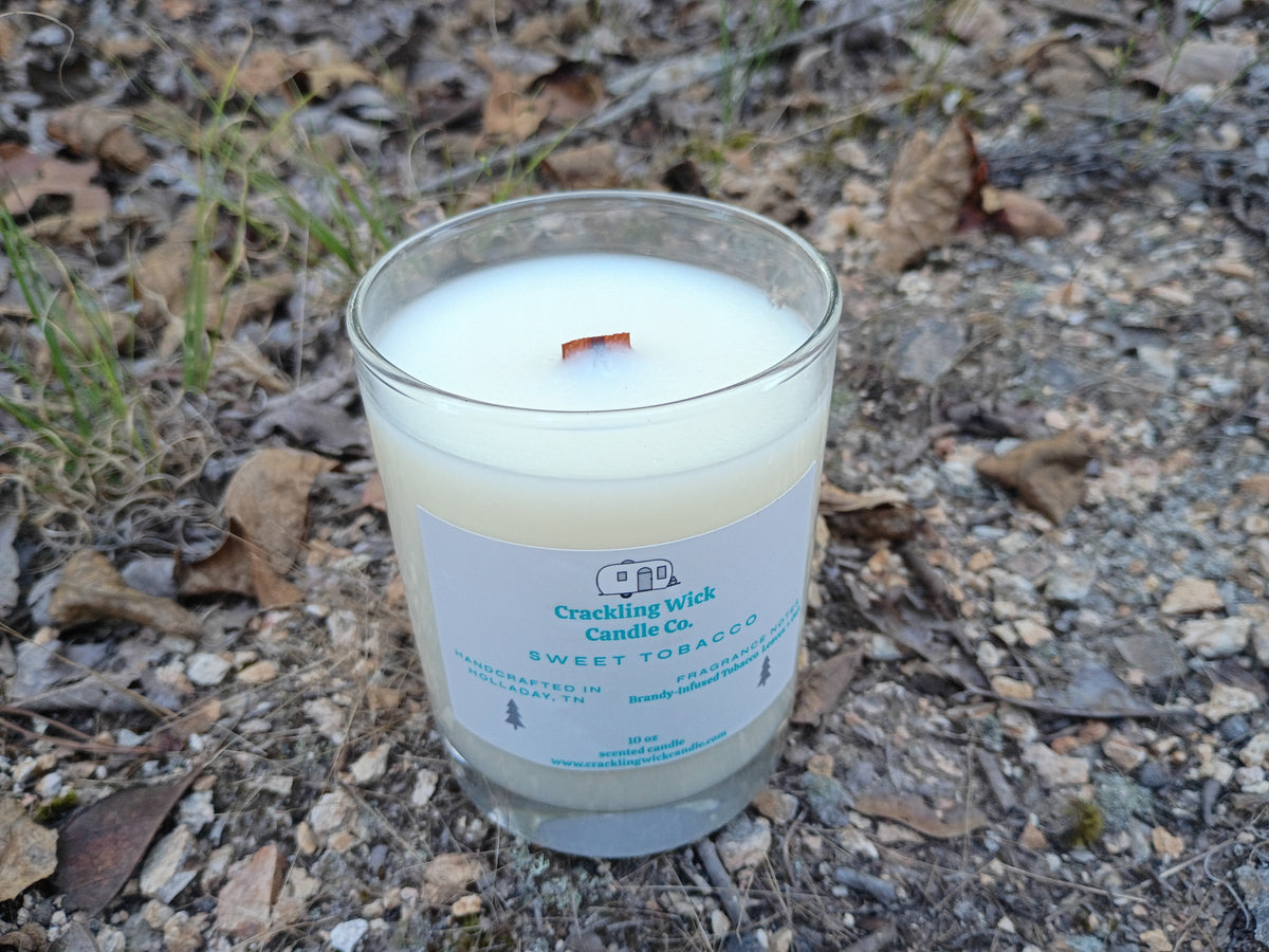Glass jar candle with white wax, crackling wick label, and a small flame