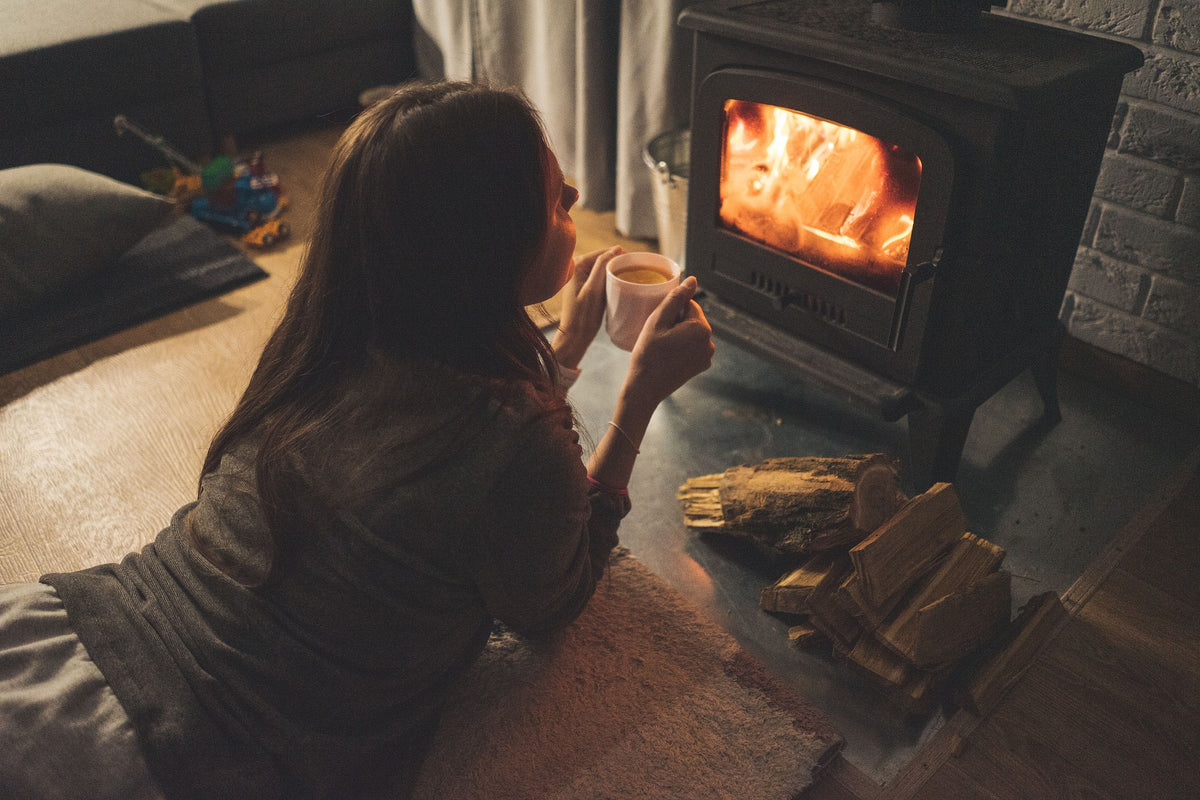 Candle flame beside fireplace with logs